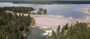 An aerial view of Island Park Dam. The reservoir sits behind it and the river flows below it.
