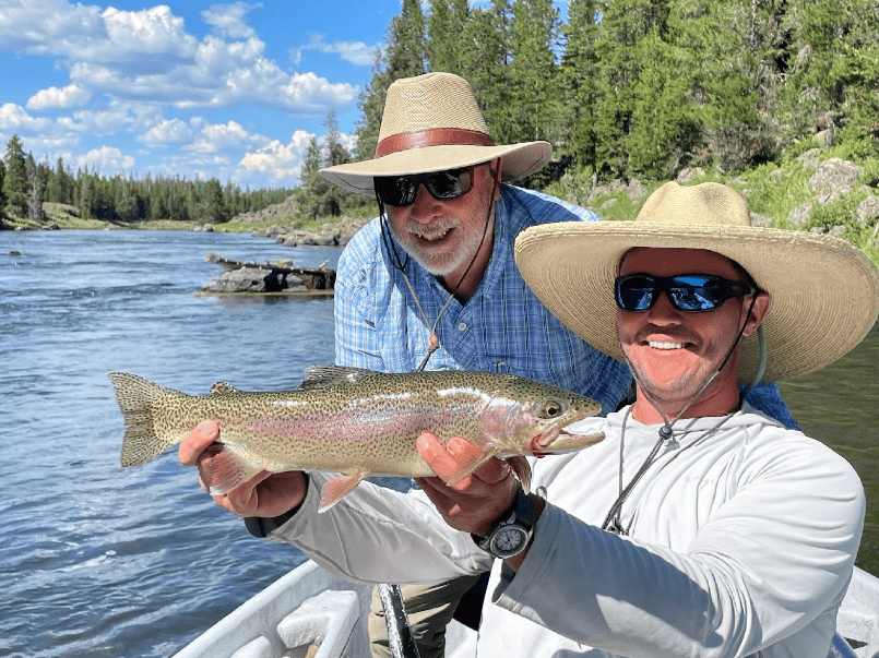 2 men smiling one of them is holding a fish